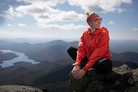 Bethany Adams sits on top of a mountain in the Adirondacks, while wearing hiking gear.