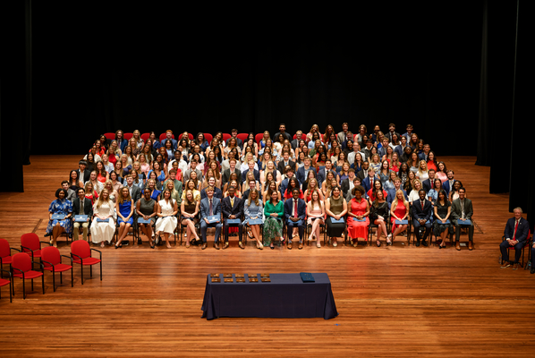 Who's Who students sit on chairs on a polished-wood stage.