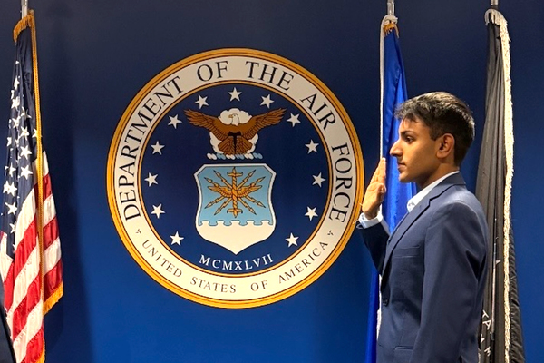 Sahil Maher ’26 salutes the American flag in front of the Department of the Airforce seal.