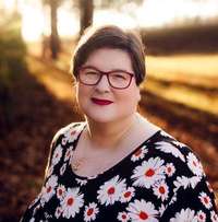 SUNY Delhi nursing professor Elizabeth Pratt wearing glasses and a floral shirt poses in golden sunlight.