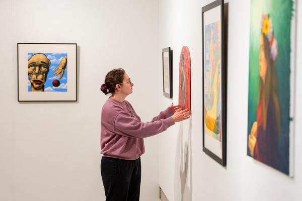Katelin Babbitt ’26, an anthropology major with an art history minor, adjusts a painting in the Gibson Gallery in preparation for the “Art Attack” show and Bachelor of Fine Arts exhibition. 