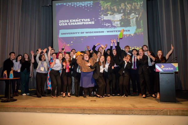 A group of college students standing and celebrating on a stage.