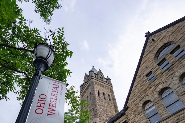 Exterior photograph of University Hall, Ohio Wesleyan's signature building, with a nearby lamp post adorned with an Ohio Wesleyan banner.