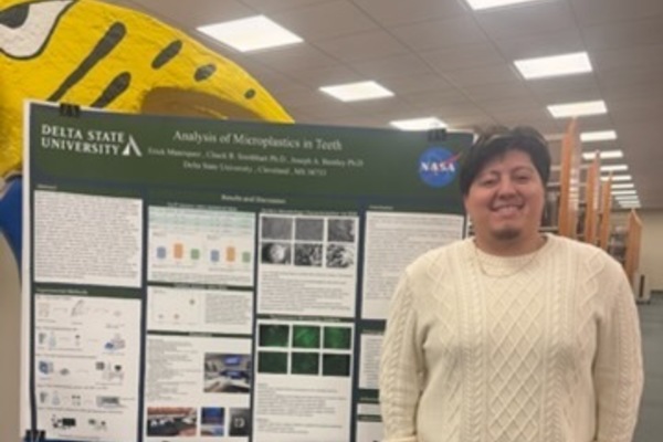 Erick Manriquez standing beside his research poster at the recent Academic Research Showcase.