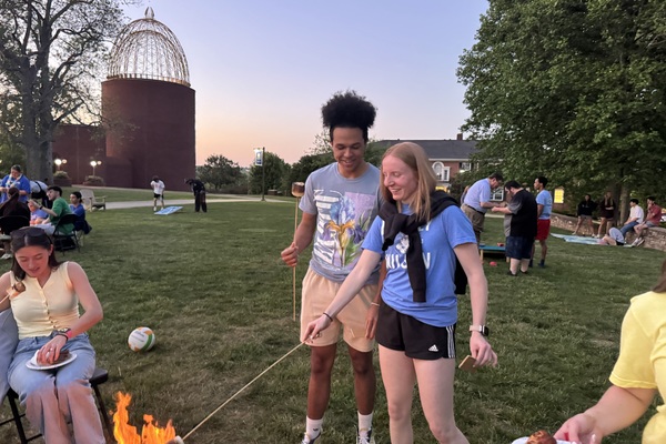 Junior Tezon Mitchell from Greensburg, Kentucky, helps senior Kyra Engel from Germany make her first-ever smore at Lindsey Wilson University’s Senior Sunset, a senior send-off event held April 22 on the campus quadrangle. 