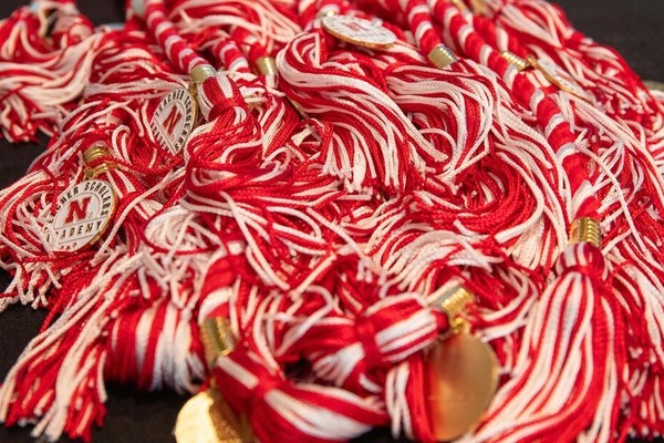 A pile of red-and-white honor cords with small medallions that say "Teacher Scholars Academy."