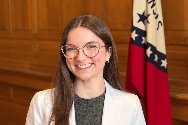 Angela Comeaux standing in a courtoom in front of the State of Arkansas flag.