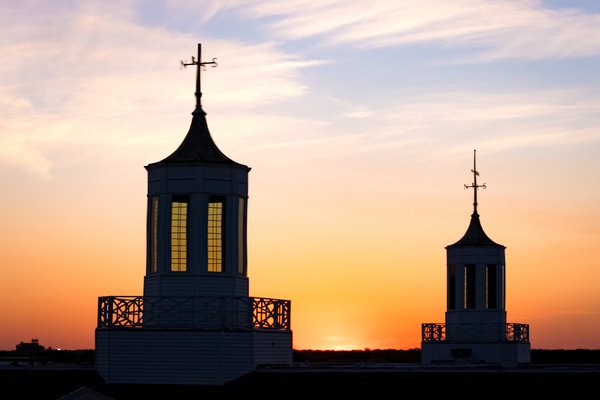 The sun rises behind the Love Library cupolas, seen in silhouette.