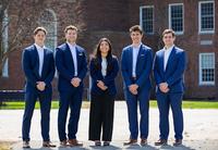 Students in business attire pose for a photo in the Academic Quad.