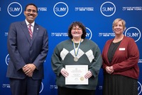 Chancellor King, Chase Bond and President Smith pose in front of a SUNY backdrop.