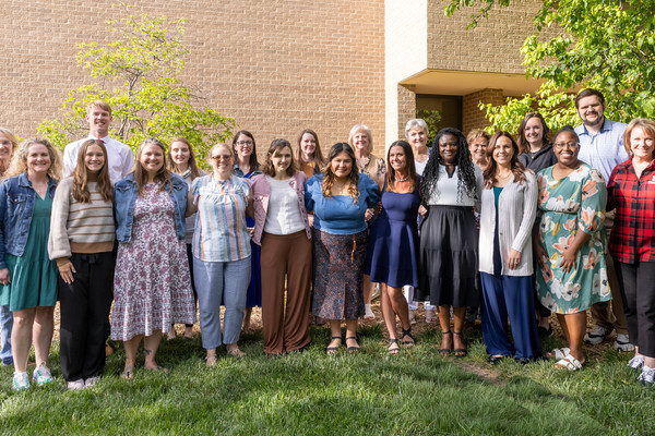 Twenty-one people, mostly women, pose for an outdoor group photo.