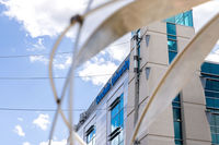 A modern building with "Goodwin University" sign, featuring large glass windows against a partly cloudy sky
