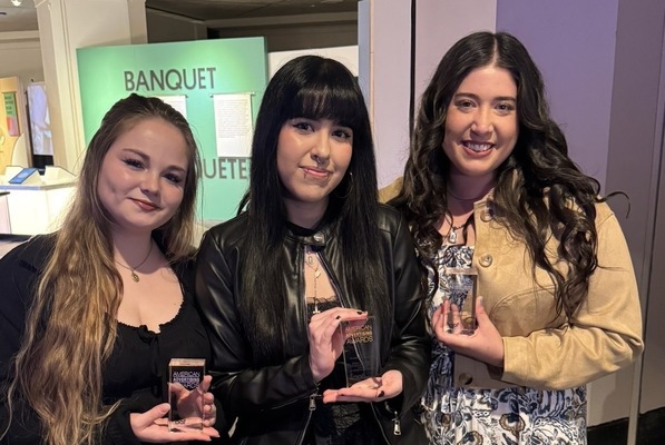 Three female students hold trophies.