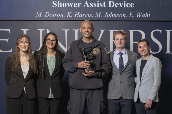 Ben Masten, center, a paramedic for the Northeast Fire District in Allen County, holds a prosthetic device developed for him by Trine University biomedical engineering students, from left, Kara Harris, Michaela Doiron, Madix Johnson and Emily Wahl. (Photo by Dean Orewiler / Trine University)