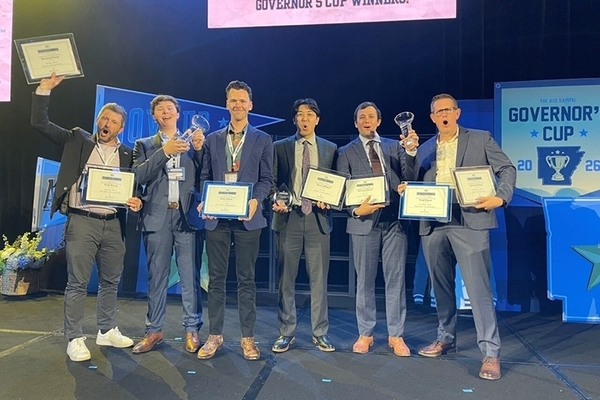 Students wearing suits on a stage holding certificates