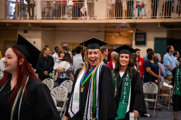 Graduates are smiling as they leave commencement ceremonies. 
