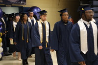 Graduates line up ready to process in for graduation, several wearing white stoles.