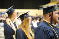 Three students lined up waiting to walk up on stage. Two women and one male.