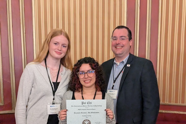 Student poses with certificate of achievement with her co-presenter and professor.