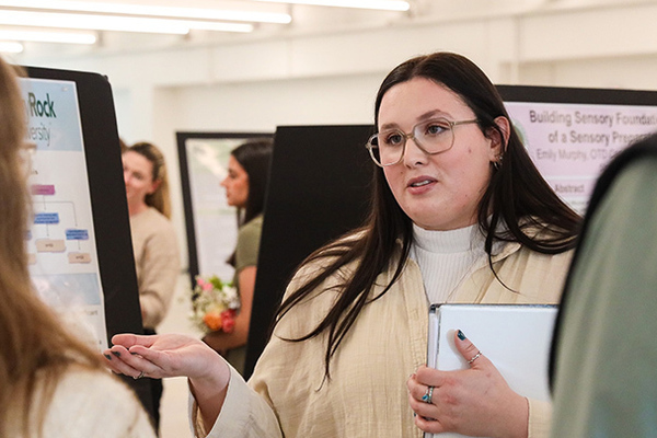 At a poster presentation event at SRU, Sophia Duncan shares her research about the underused application occupational therapy in oncology.