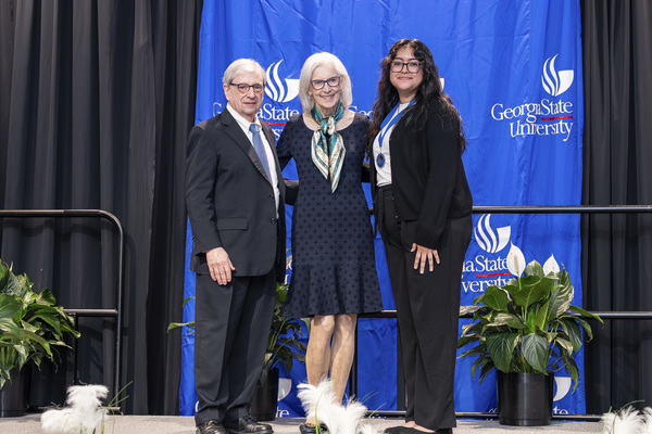 Paul Alberto, Cynthia Kuhlman and award recipient Osiris Zelaya pose for a photo on stage at the college's 2026 Scholars Recognition Luncheon. 