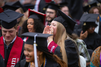 A graduate dressed in her SUNY Potsdam robe and mortarboard cheers during Commencement.