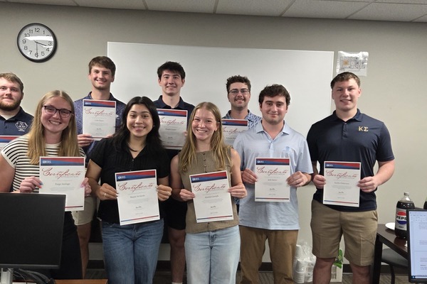 Nine students holding certificates stating they are certified to prepare taxes at VITA site