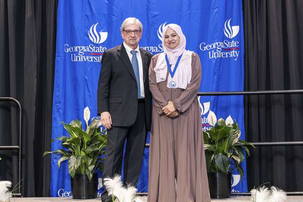 Paul Alberto and award recipient Mina Uddin pose for a photo on stage at the college's 2026 Scholars Recognition Luncheon.
