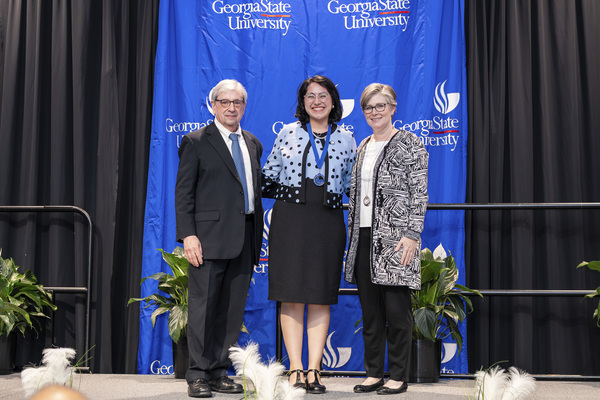 Paul Alberto, Alexis Alvarez and Caitlin Dooley pose for a photo on stage at the college's 2026 Scholars Recognition Luncheon. 