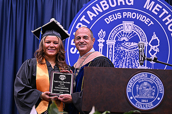 College president awards student plaque for class leader award.