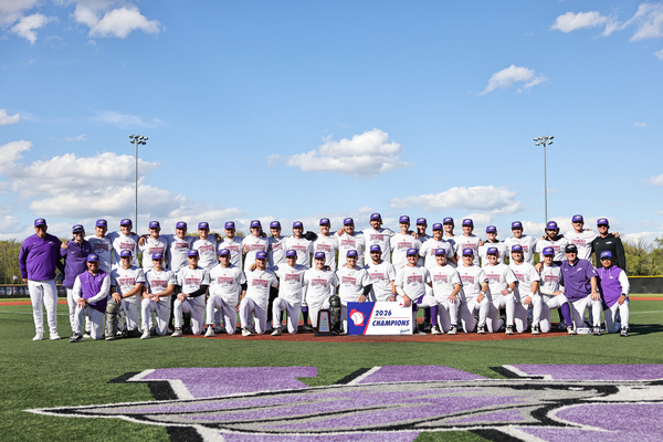 A group of college baseball players poses for a photo with a banner and championship trophy.