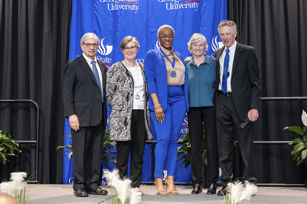 Paul Alberto, Caitlin Dooley, Tyneshia Flennory and Julie and Harry Dangel pose for a photo on stage at the 2026 Scholars Recognition Luncheon.