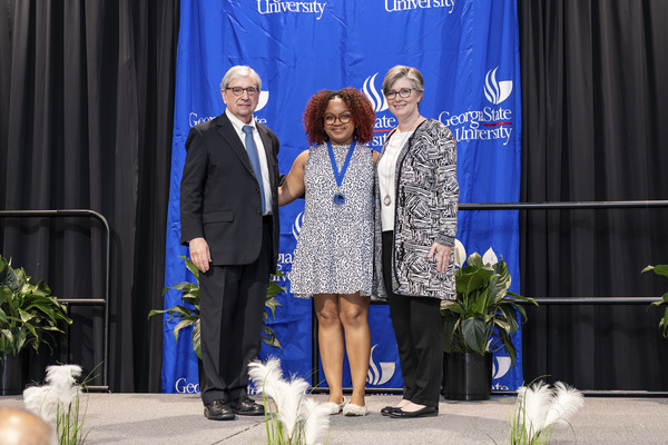 Paul Alberto, Briana Hall and Caitlin Dooley pose for a photo on stage at the college's 2026 Scholars Recognition Luncheon.