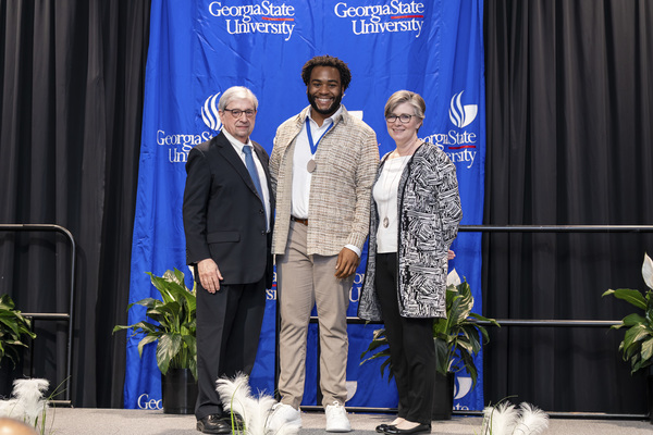 Paul Alberto, Jonathan Smith and Caitlin Dooley pose for a photo on stage at the college's 2026 Scholars Recognition Luncheon.