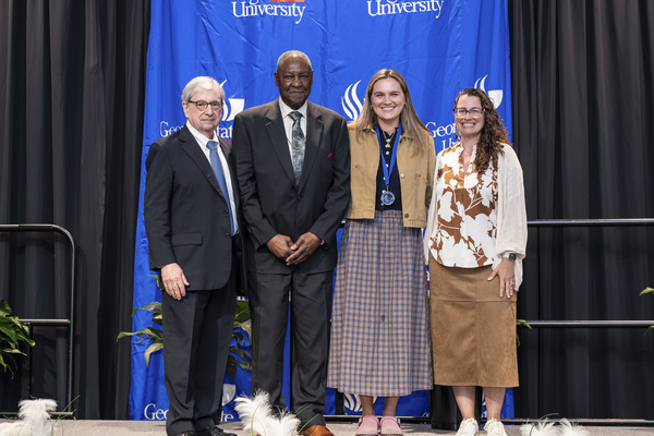 Paul Alberto, Rev. Robert Tolbert, Mallie Egan and Jennifer Esposito pose for a photo on stage at the college's 2026 Scholars Recognition Luncheon.