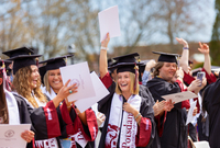 Graduates cheer and hold up their diplomas at SUNY Potsdam's Commencement. Emily Jordon is in the center.