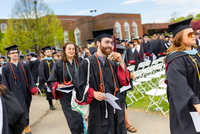 Jason Donovan smiles while walking with fellow graduates through a funnel of faculty members at Commencement.
