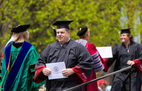 Jeff Yette crosses the stage at Commencement, holding his diploma.