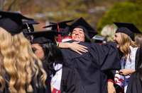 Ella Hutchins hugs a friend while wearing her cap and gown.