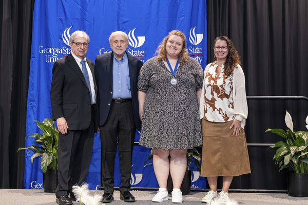 Paul Alberto, John Neel, Hannah Scarbrough and Jennifer Esposito pose for a photo on stage at the college's 2026 Scholars Recognition Luncheon. 
