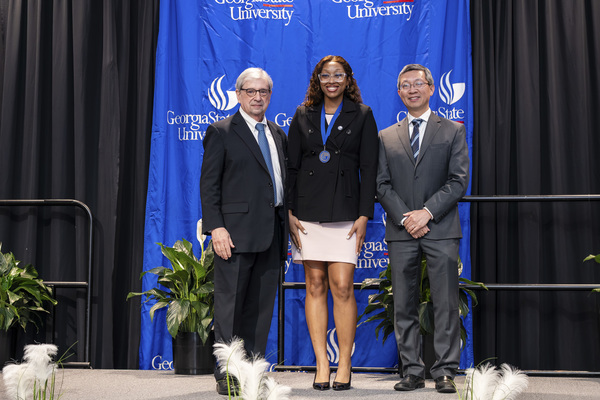 Paul Alberto, Destiny Barnes and Jerry Wu pose for a photo on stage at the college's 2026 Scholars Recognition Luncheon.