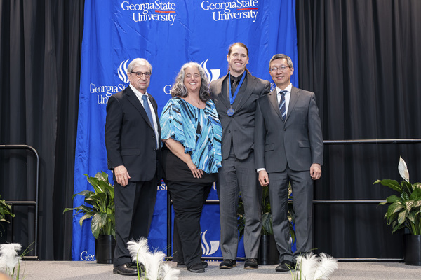 Paul Alberto, Amy Windham, Andrew Corbett and Jerry Wu pose for a photo on stage at the college's 2026 Scholars Recognition Luncheon.