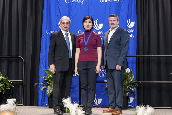 Paul Alberto, Eleanor Fang Yan and Brendan Calandra pose for a photo on stage at the college's 2026 Scholars Recognition Luncheon. 
