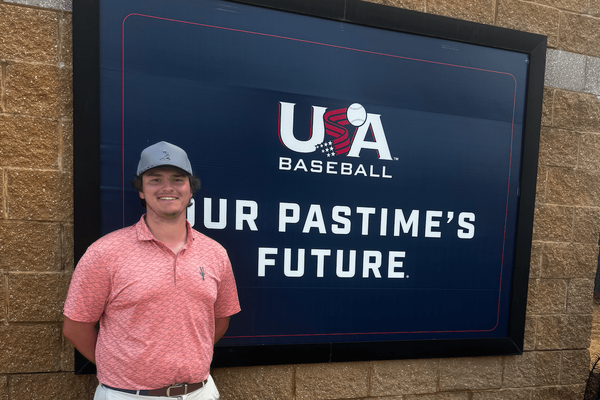 A Shenandoah student stands in front of a screen featuring the USA Baseball logo and the phrase "Our Pastime's Future."