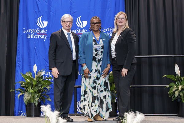 Paul Alberto, Dishelesh Jones and Reneé Schwartz pose for a photo on stage at the college's 2026 Scholars Recognition Luncheon.