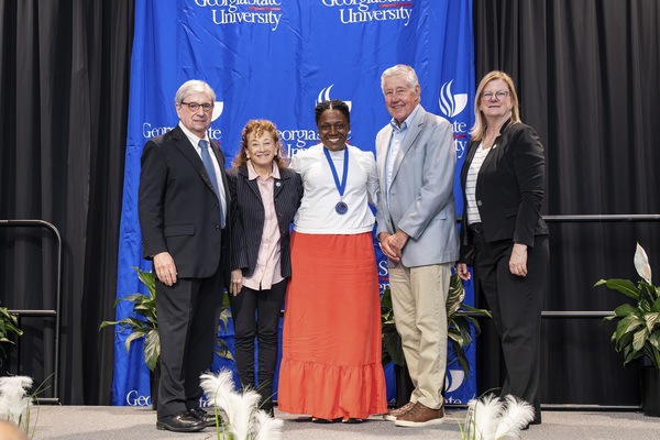Paul Alberto, Babs Johnston, Krista Saunders, Hiram Johnston and Reneé Schwartz pose for a photo on stage at the 2026 Scholars Recognition Luncheon.