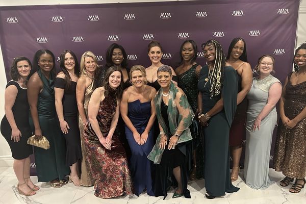 Kettering University Students pose in formal attire in front of a backdrop at the Automotive Women’s Alliance Foundation 30th Anniversary Gala.