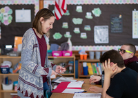 A teacher works with students in a school classroom.