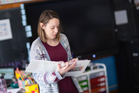 A teacher works with students in a school classroom.