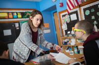 A teacher works with students in a school classroom.